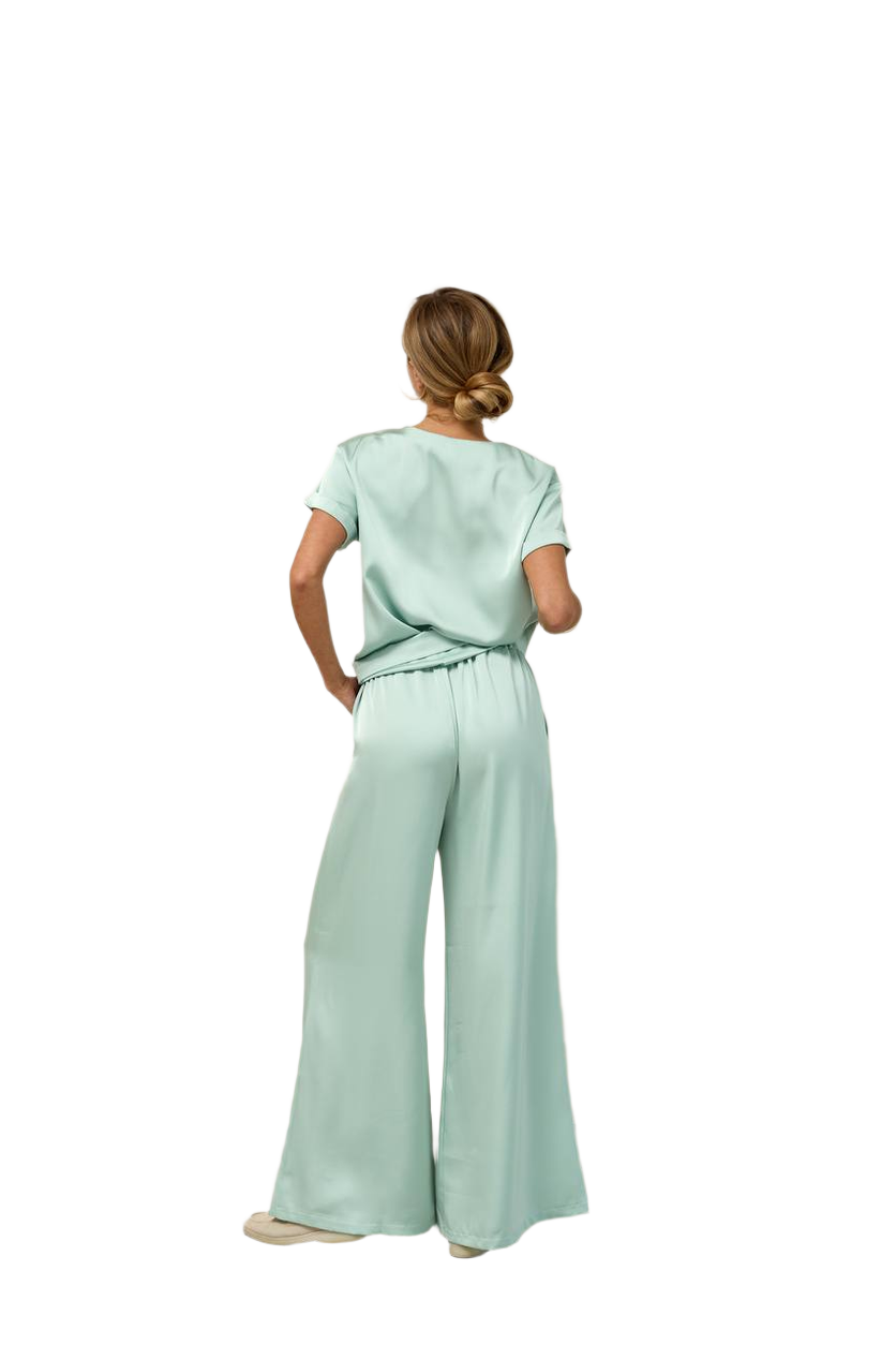 Woman wearing a light green outfit with wide-leg pants on a white background