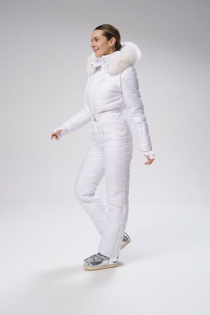 Woman wearing a white snowsuit with fur hood on a gray background