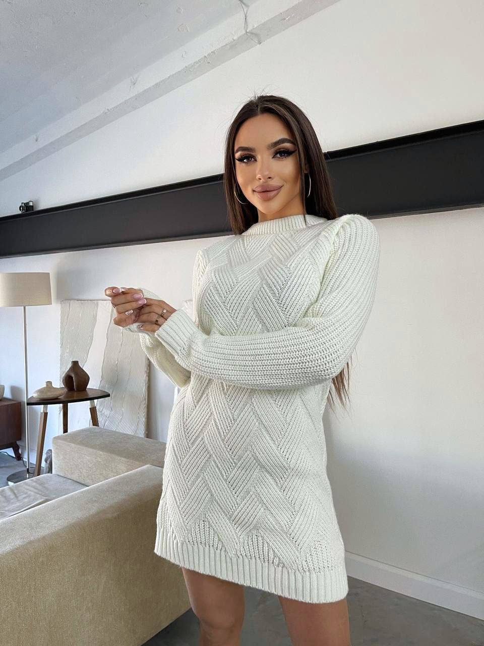 Woman wearing a light green knitted dress in a modern living room.