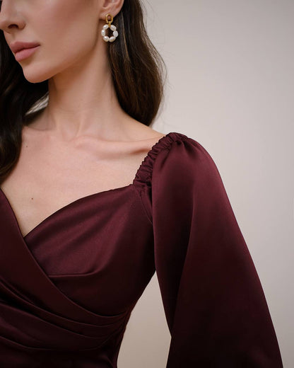 Close-up of a woman wearing a burgundy dress with a plain background