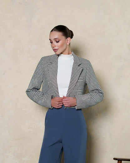 Woman wearing a checkered blazer and blue pants against a beige background