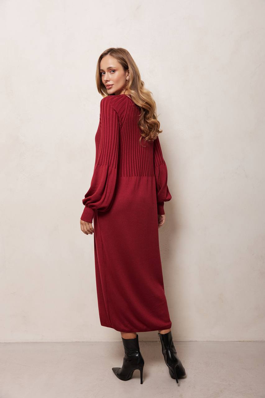 Woman wearing a red dress with long sleeves against a plain background