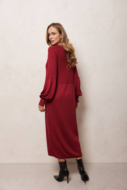 Woman wearing a red dress with long sleeves against a plain background