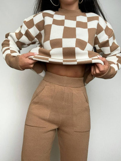 Person wearing a brown and white checkered sweater and matching pants against a plain background