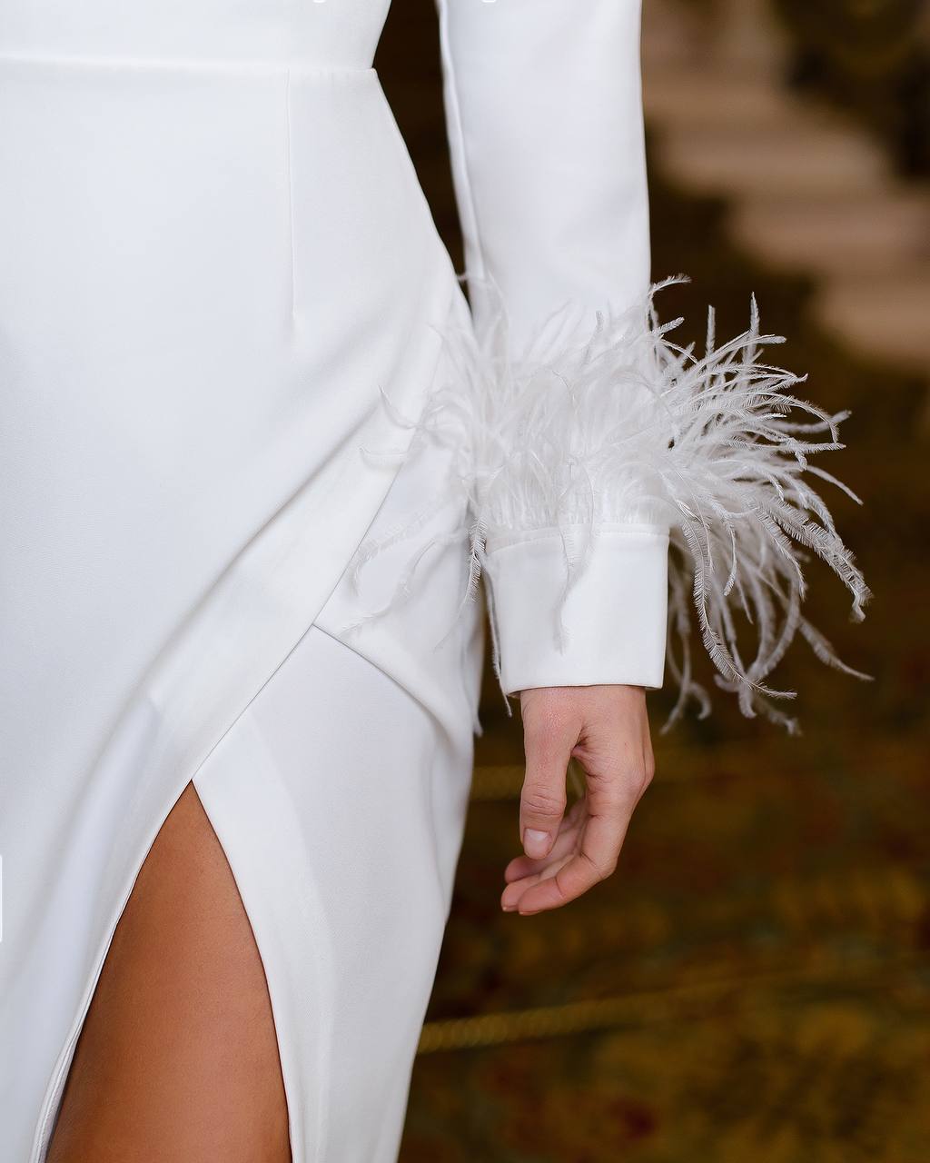 White dress with feathered cuffs on a blurred background