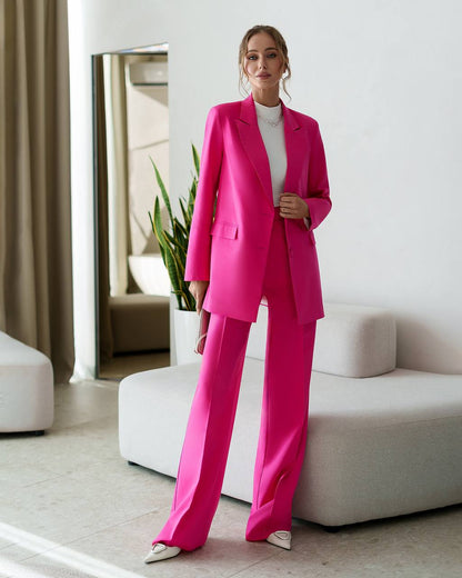 Woman in a bright pink suit standing in a modern living room.