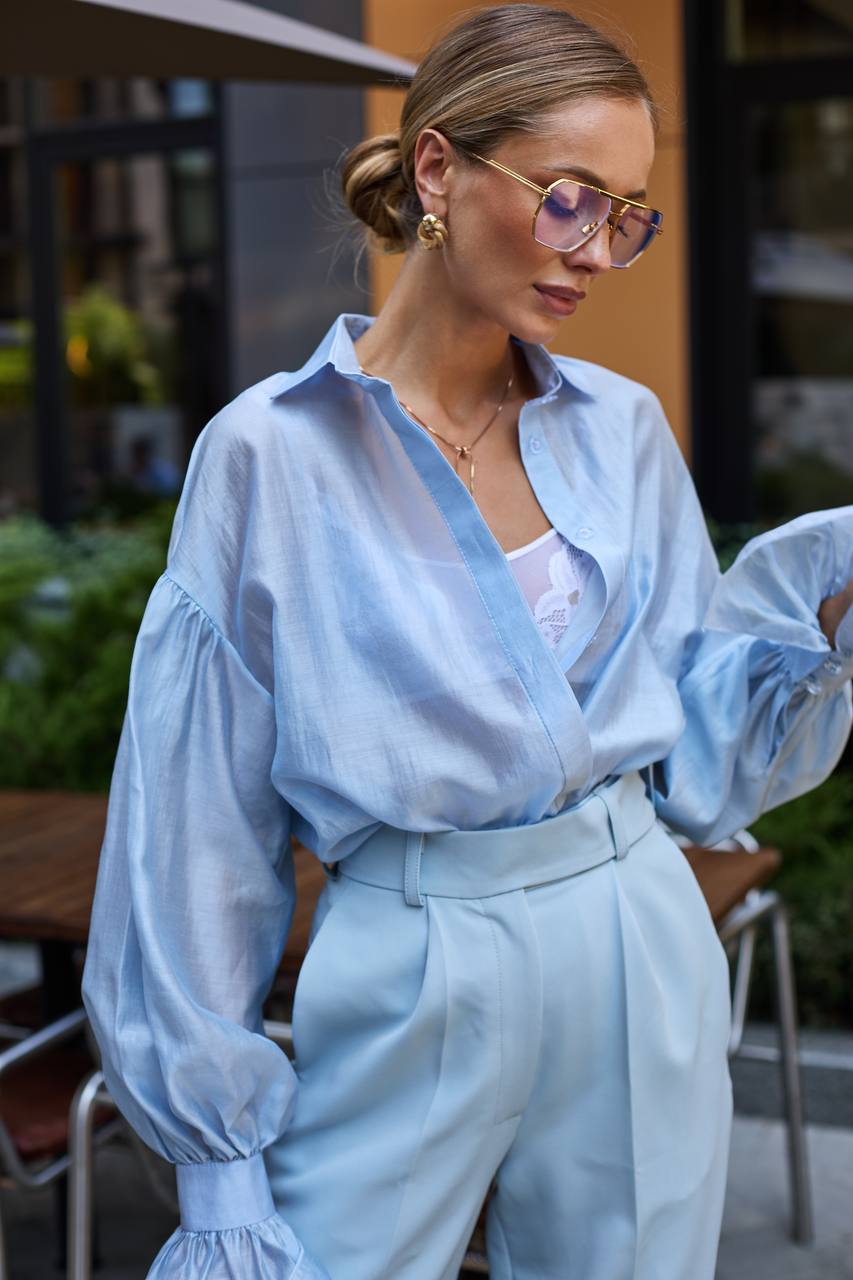 Woman wearing a light blue outfit with a blurred outdoor background