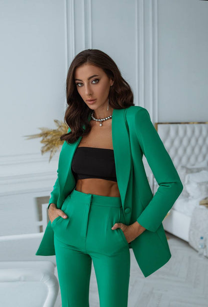 Woman wearing a green suit with a black top in an indoor setting