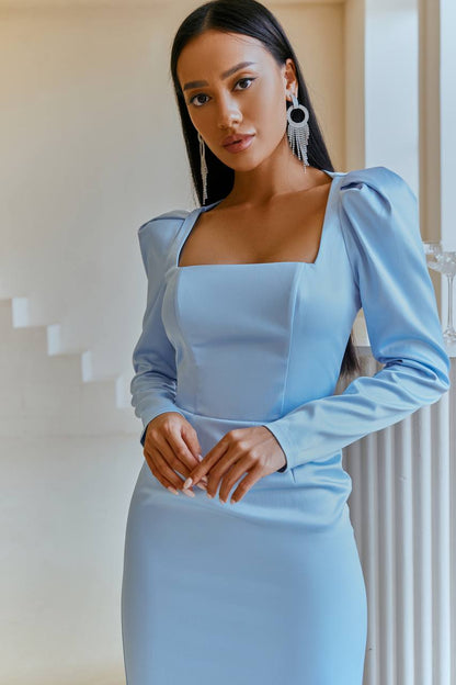 Woman wearing a light blue dress with long sleeves in an indoor setting