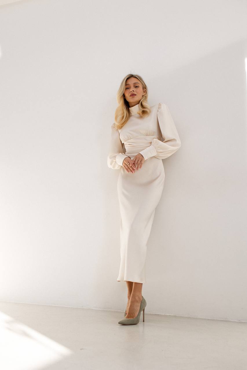 Woman wearing a white dress with a high collar against a white background