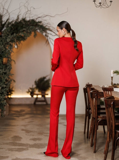 Woman in a red outfit standing in a room with a dining table and decorative plants.