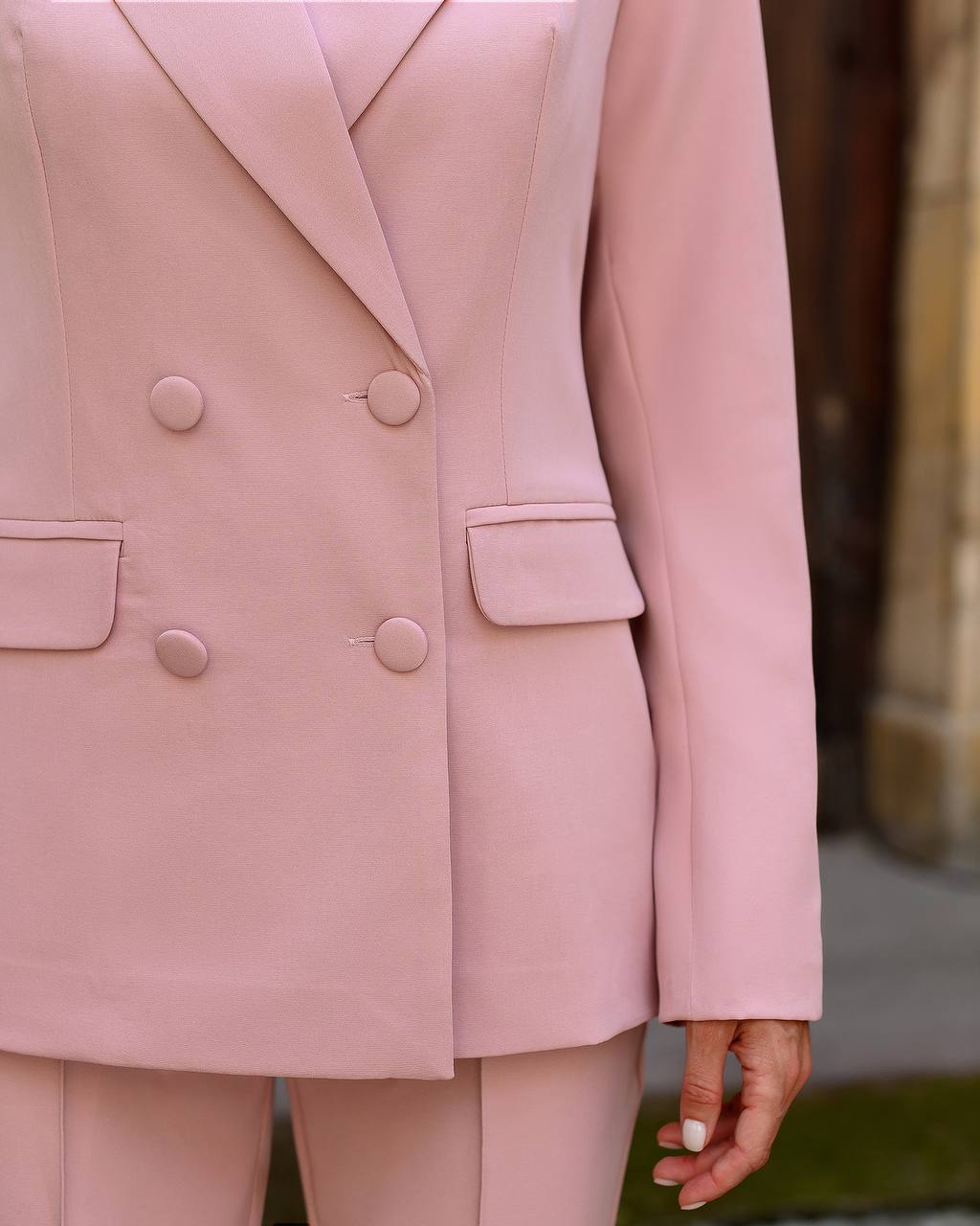 Close-up of a pink blazer with buttons and a pocket.