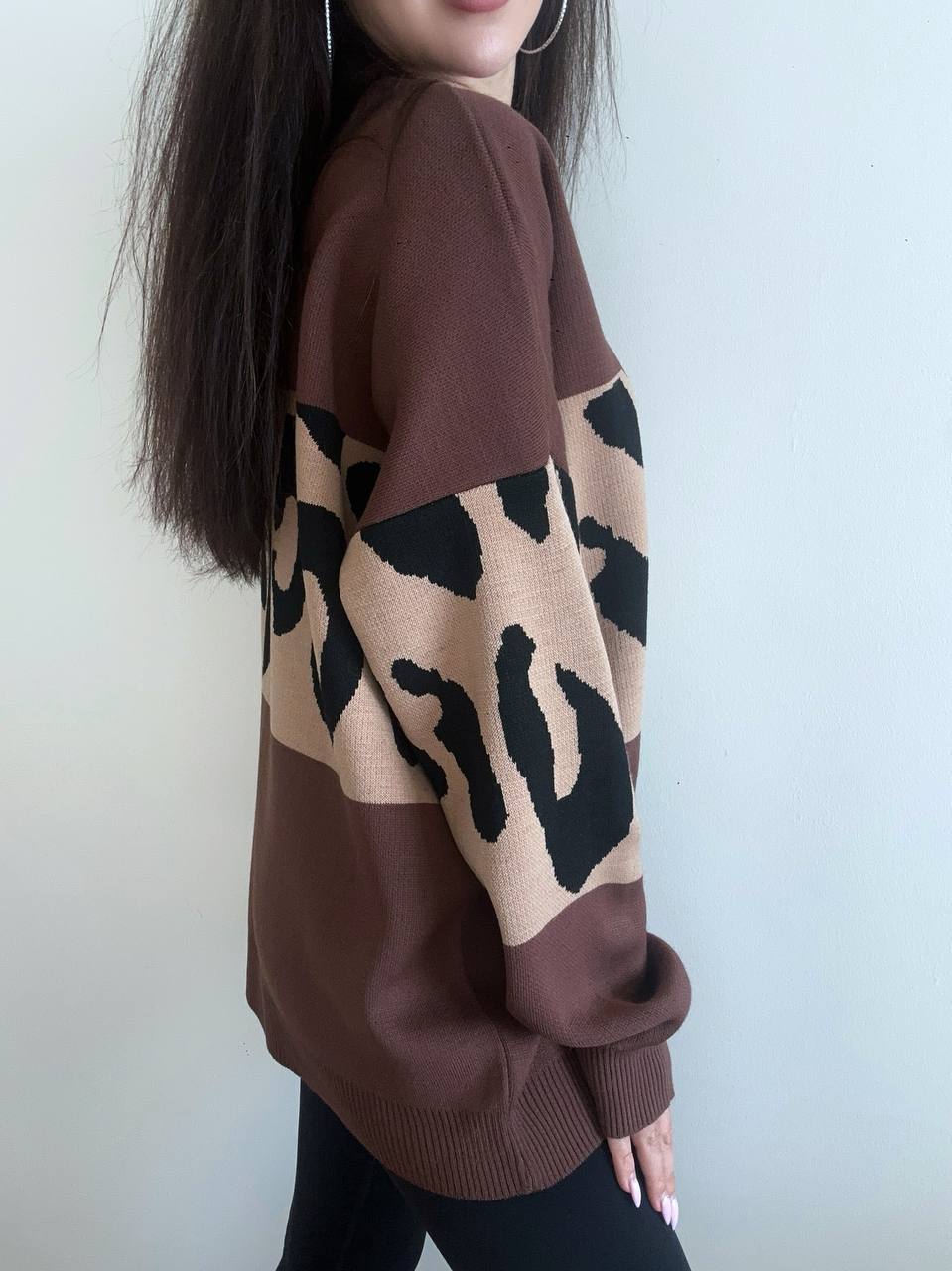Person wearing a brown sweater with leopard print pattern against a white background