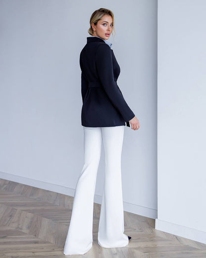 Woman wearing a navy blazer and white pants in a minimalistic setting