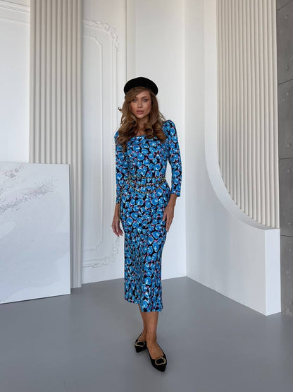 Woman wearing a blue floral dress and black shoes in a minimalistic setting