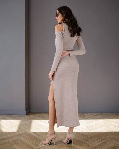 Woman wearing a long, off-shoulder dress with a high slit on a wooden floor.