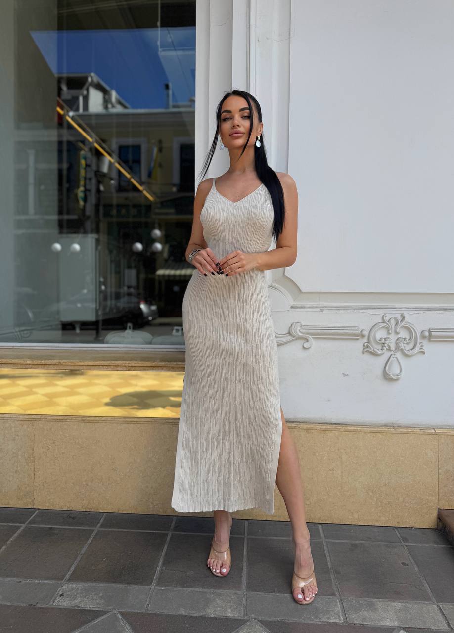 Woman in a white dress standing in front of a building entrance.
