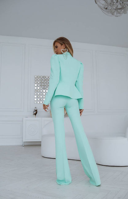 Woman wearing a mint green suit in a minimalistic room.