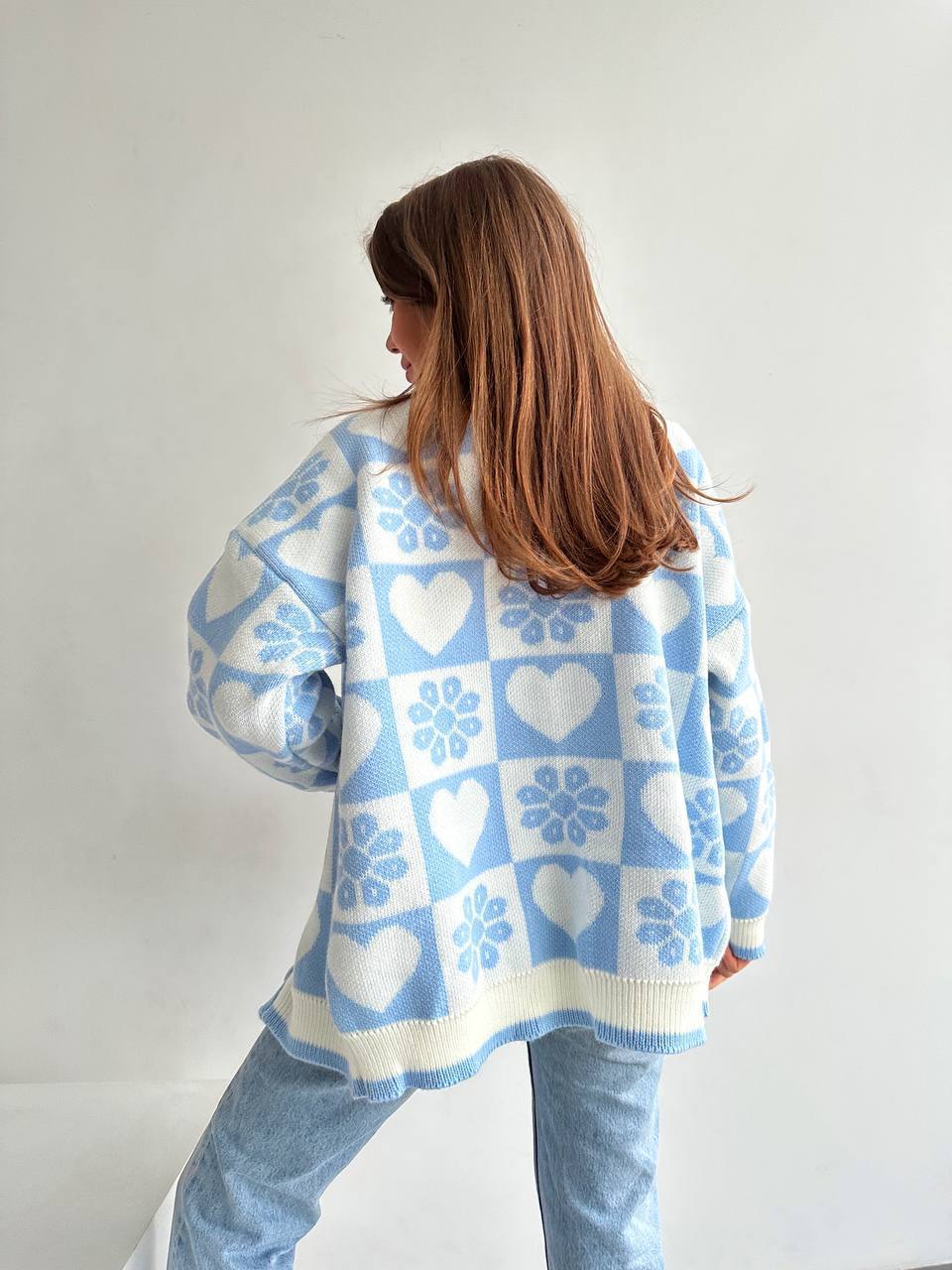 Person wearing a blue and white patterned sweater against a plain background