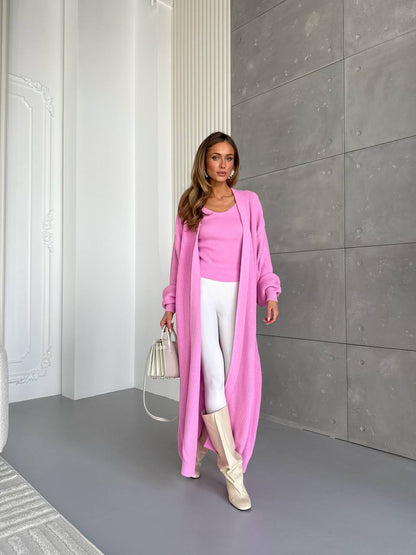 Woman in a pink outfit standing against a gray wall.