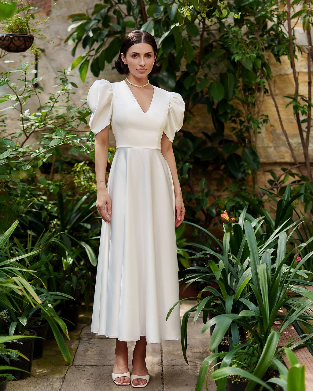 Woman in a white dress standing in a garden setting