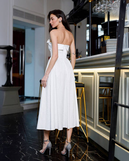 Woman in a white dress standing in an elegant interior setting