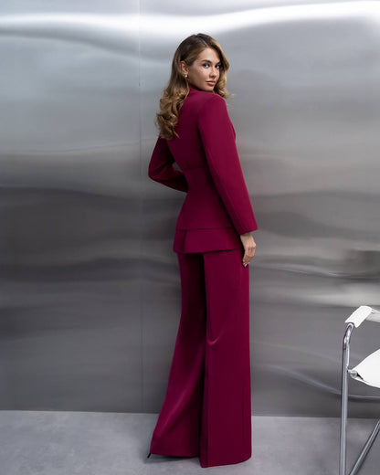 Woman in a burgundy suit standing against a metallic silver background