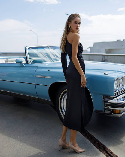 Woman in a black dress standing next to a blue vintage car on a rooftop.