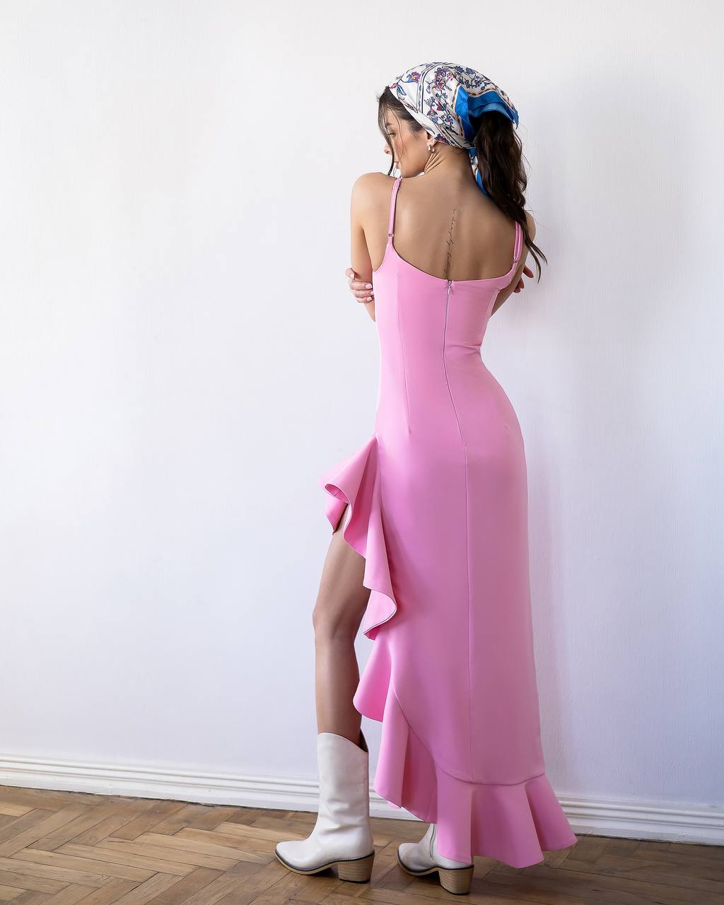 Woman wearing a pink dress with a white wall background