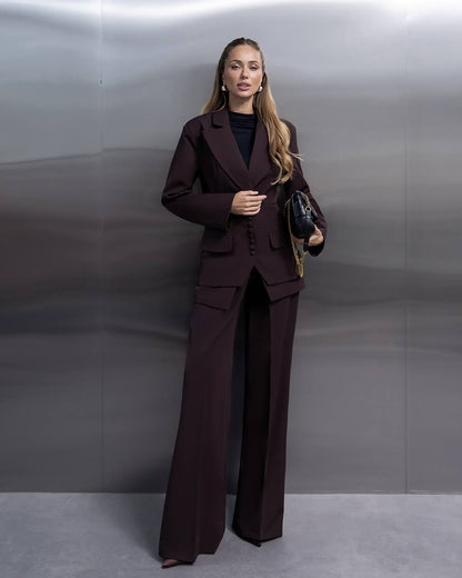 Woman wearing a dark brown suit against a plain background