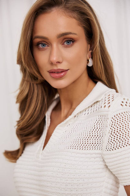 Woman wearing a white textured top against a plain background