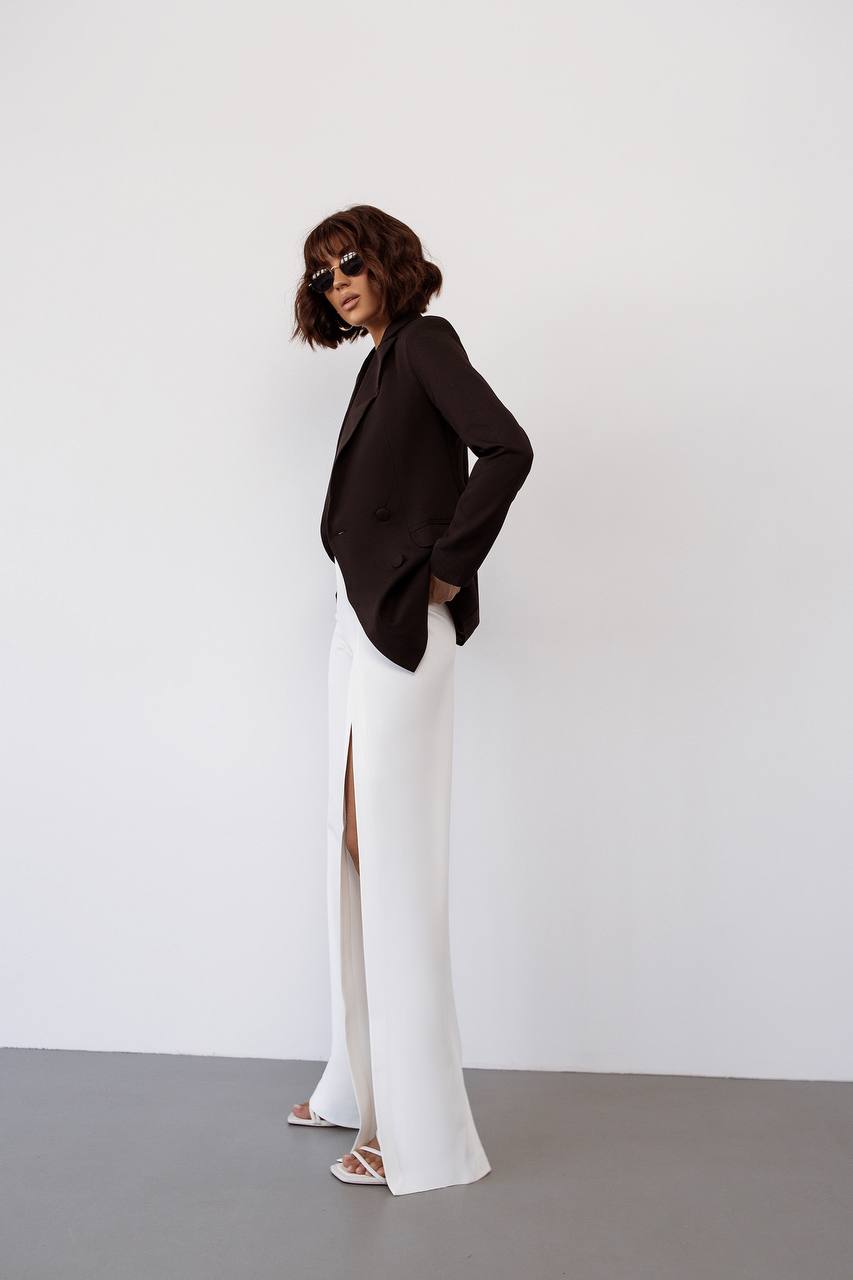 Person wearing a black blazer and white pants against a white background