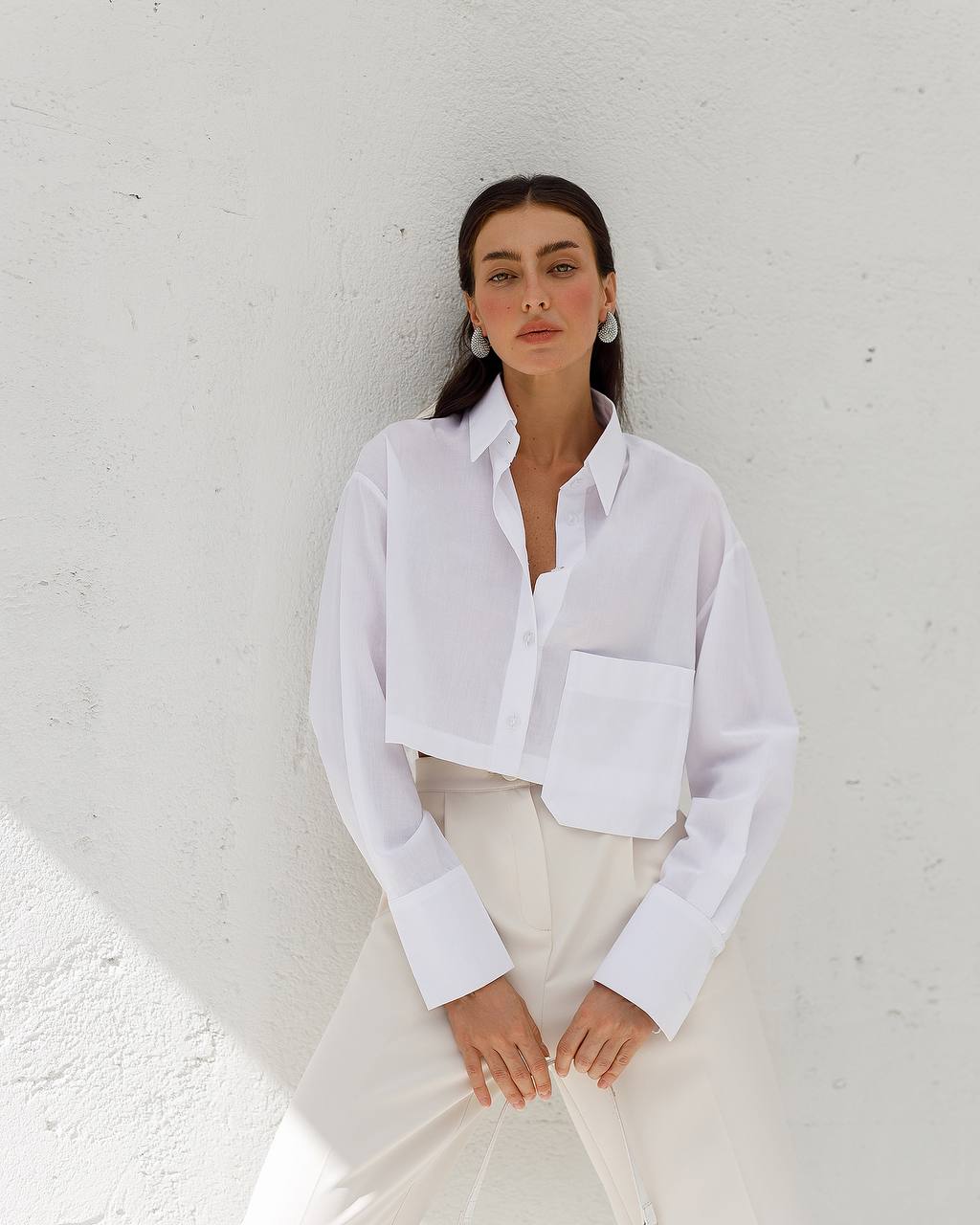Woman wearing a white shirt against a white wall