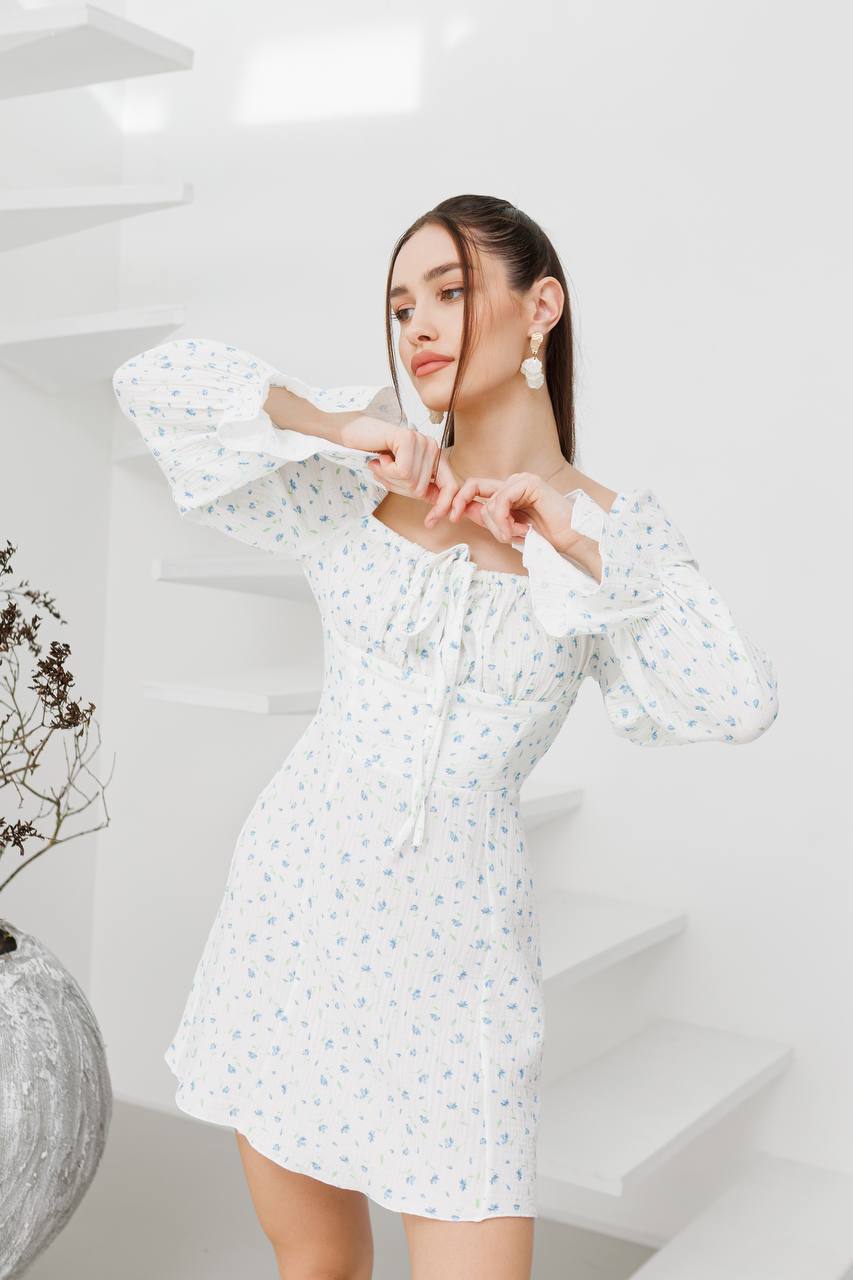 Woman wearing a white floral dress in a minimalistic setting