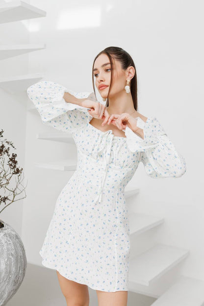 Woman wearing a white floral dress in a minimalistic setting