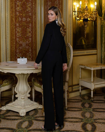 Woman in a black outfit standing in an ornate room with decorative walls and furniture.
