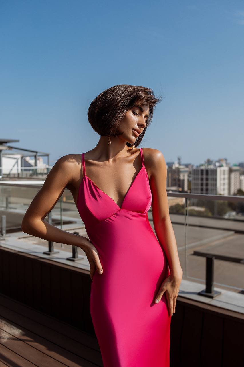 Woman in a pink dress standing on a rooftop with a cityscape background