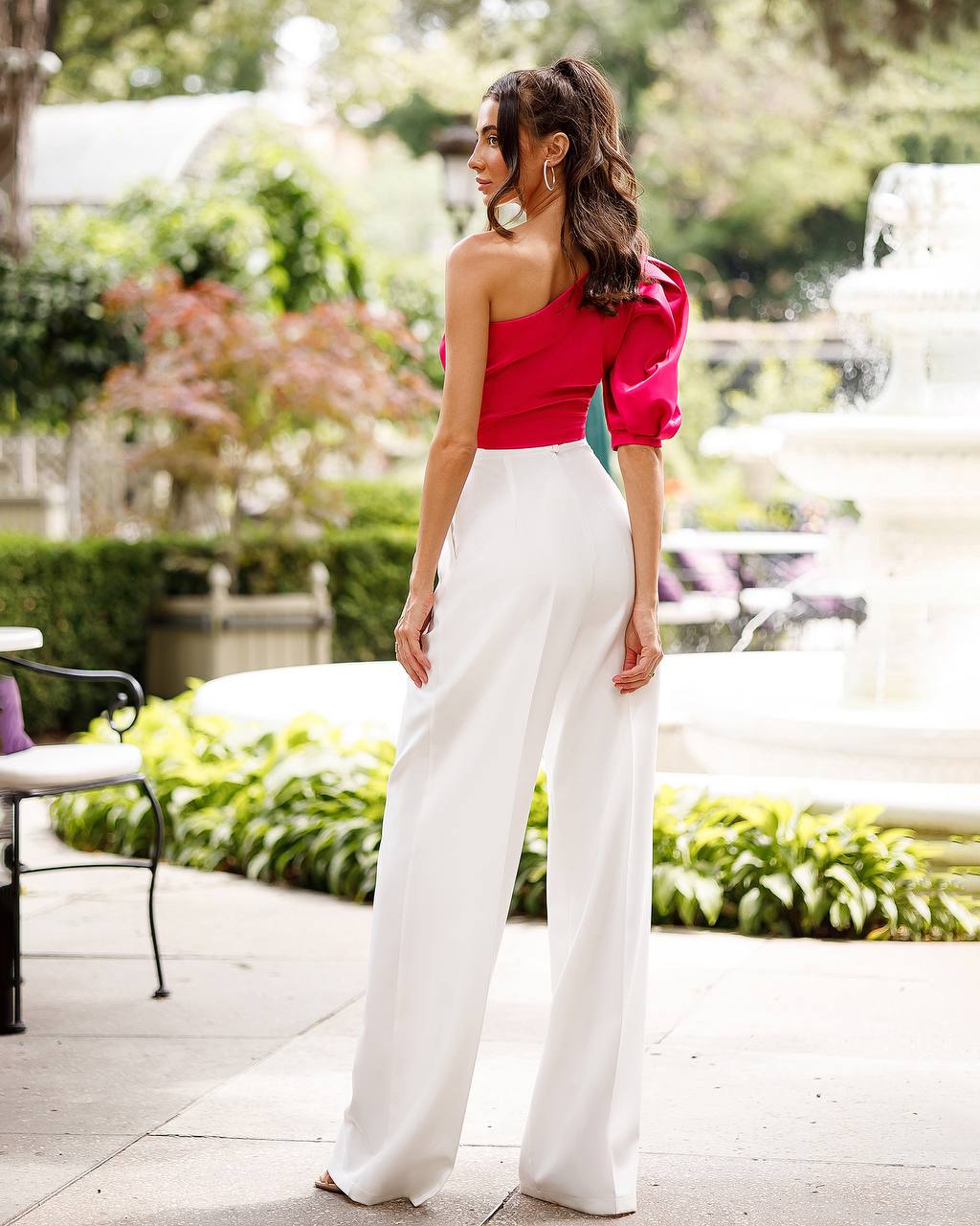 Woman wearing a red top and white pants in an outdoor setting