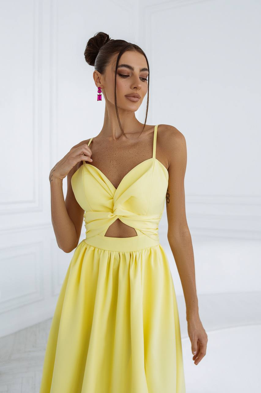 Woman wearing a yellow dress with cut-out design against a white background