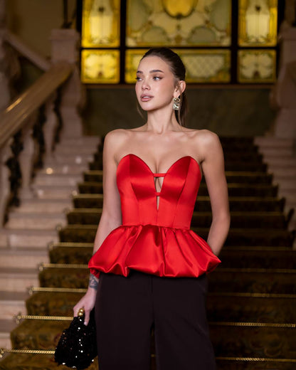 Woman in a red dress standing on a staircase with ornate decorations.