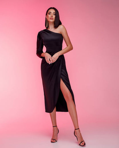 Woman wearing a black one-shoulder dress with a slit on a pink background