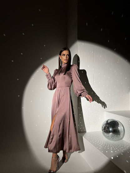 Woman in a long, light purple dress standing in a spotlight with a disco ball in the background.