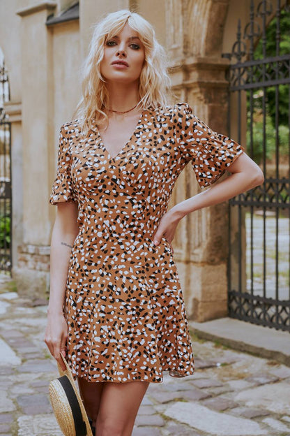 Woman wearing a patterned dress standing outdoors with architectural elements in the background