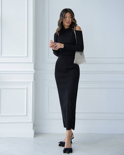 Woman wearing a black outfit with a white wall background