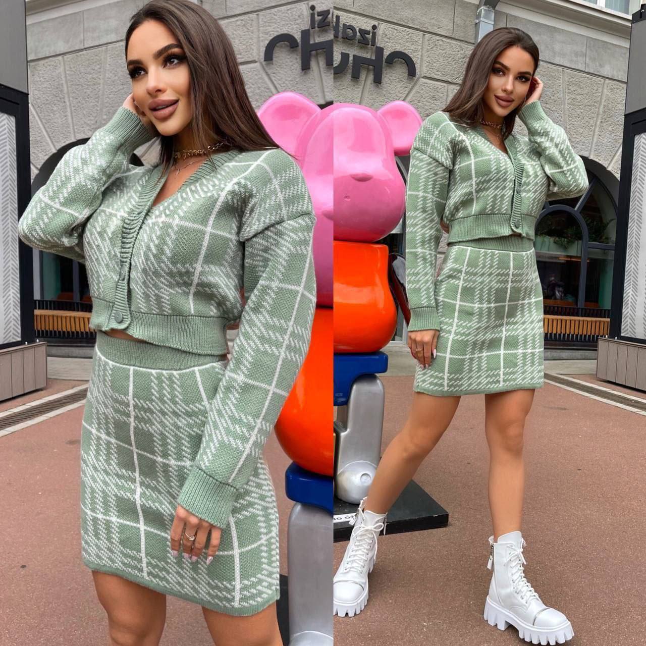 Woman in a green plaid outfit standing in front of colorful playground equipment.