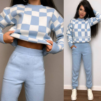 Woman wearing a blue and white checkered sweater and pants set against a neutral background.