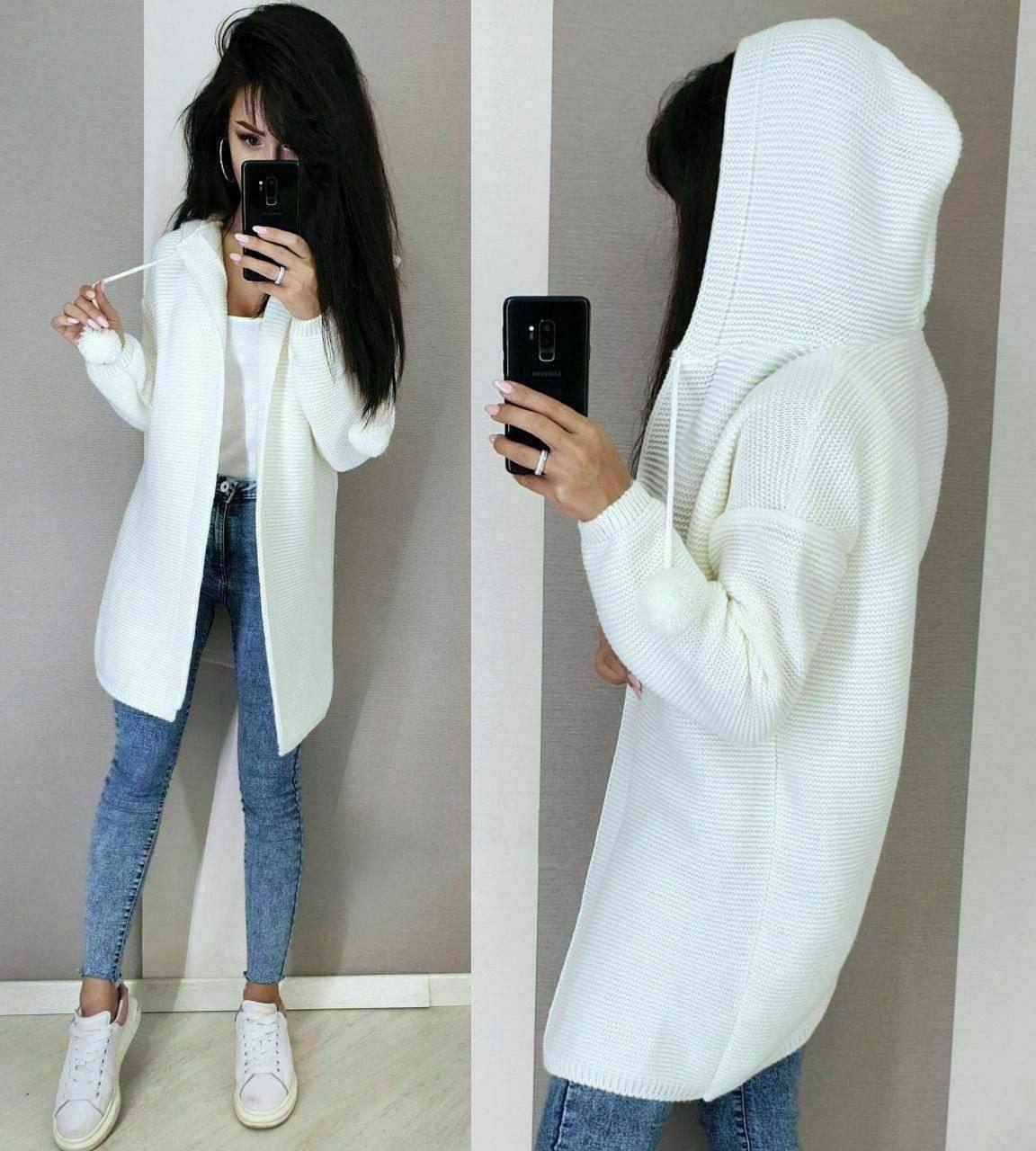 Person wearing a white hoodie and blue jeans, taking a mirror selfie.
