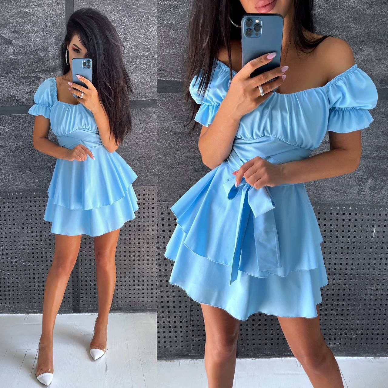 Woman wearing a light blue dress with ruffled sleeves and skirt, taking a mirror selfie.
