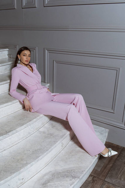 Woman in a pink suit sitting on a staircase with gray paneled walls.