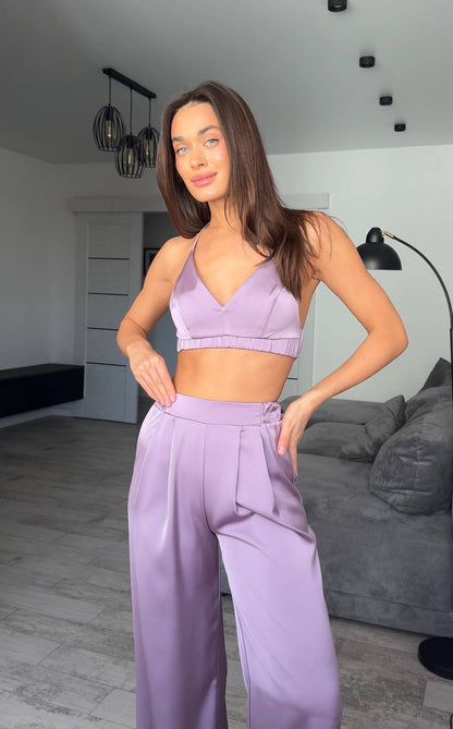 Woman wearing a purple sports bra and pants in a modern living room.